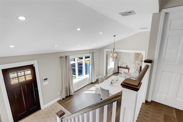 entrance foyer with vaulted ceiling, wood finished floors, visible vents, and an inviting chandelier