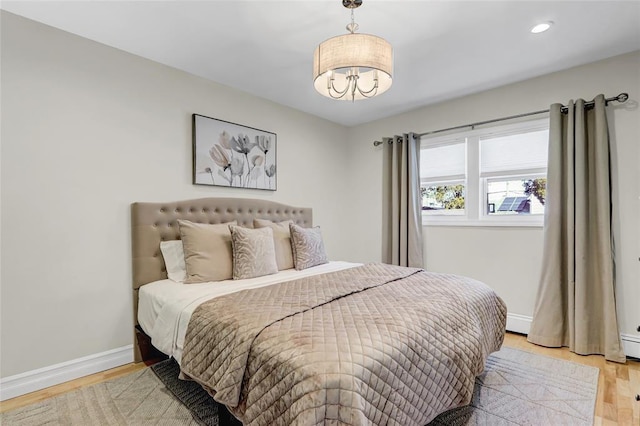 bedroom with light wood-type flooring, an inviting chandelier, baseboards, and recessed lighting