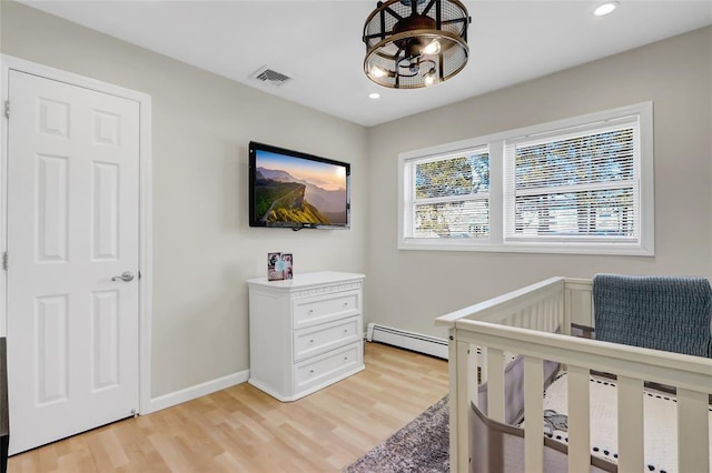 bedroom featuring a nursery area, recessed lighting, visible vents, a baseboard heating unit, and light wood-type flooring