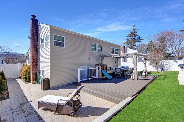 rear view of property featuring a lawn, a fenced backyard, a wooden deck, and a pergola