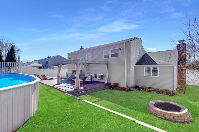 back of house featuring a deck, a fenced backyard, a fire pit, a pergola, and a chimney