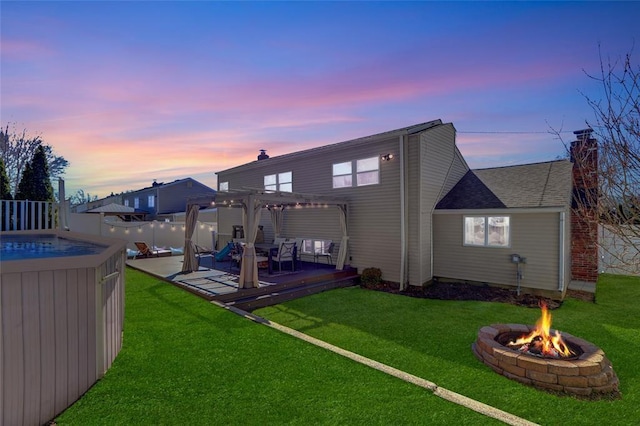 back of property at dusk with an outdoor fire pit, fence, a chimney, and a pergola