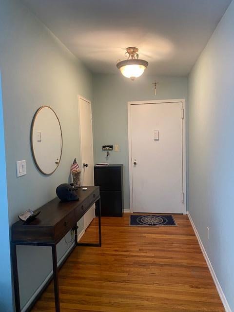 doorway with wood finished floors and baseboards