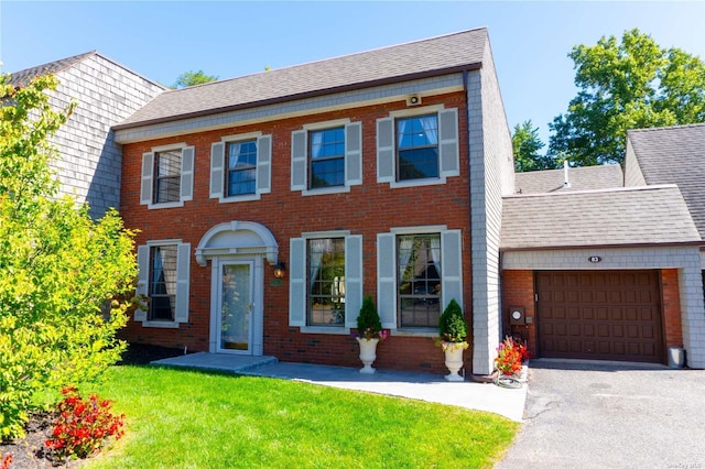 view of front of property featuring a shingled roof, brick siding, an attached garage, and a front lawn