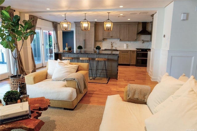 living room featuring light wood-type flooring, wainscoting, a decorative wall, and recessed lighting