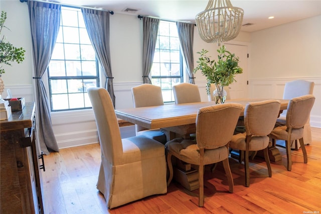 dining area featuring light wood-type flooring, plenty of natural light, visible vents, and a chandelier