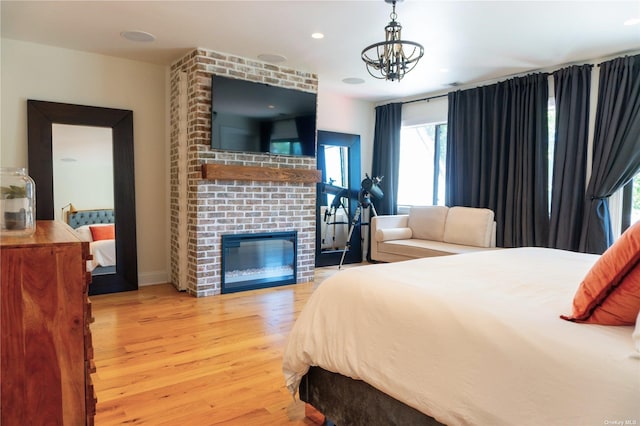 bedroom with recessed lighting, a brick fireplace, wood finished floors, and a notable chandelier