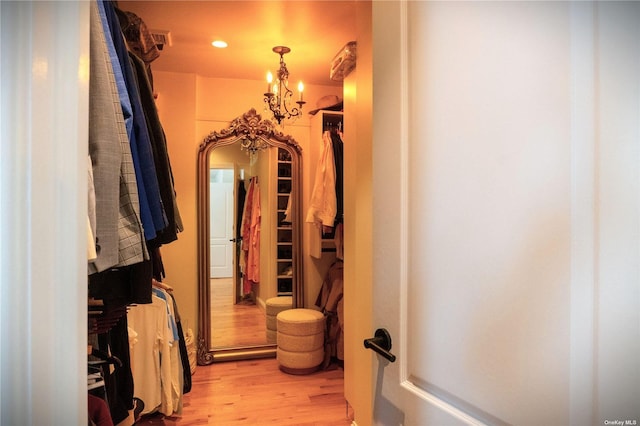 walk in closet featuring light wood finished floors, visible vents, and a chandelier