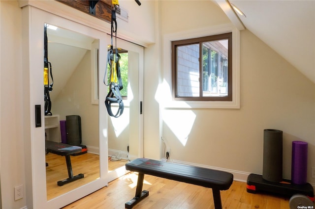 exercise area with lofted ceiling, hardwood / wood-style floors, and baseboards