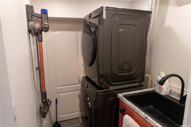 laundry room featuring laundry area, stacked washer and dryer, and a sink