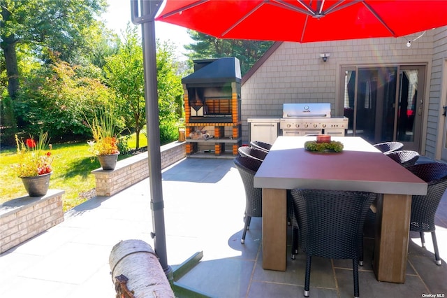 view of patio featuring exterior kitchen, outdoor dining space, a fireplace, and a grill