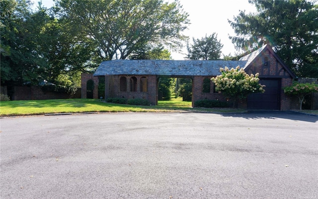 view of front facade featuring a garage, aphalt driveway, a front lawn, and brick siding