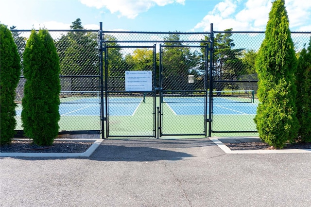 view of tennis court featuring fence and a gate