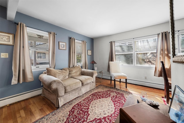 living area with a baseboard heating unit, plenty of natural light, and wood finished floors