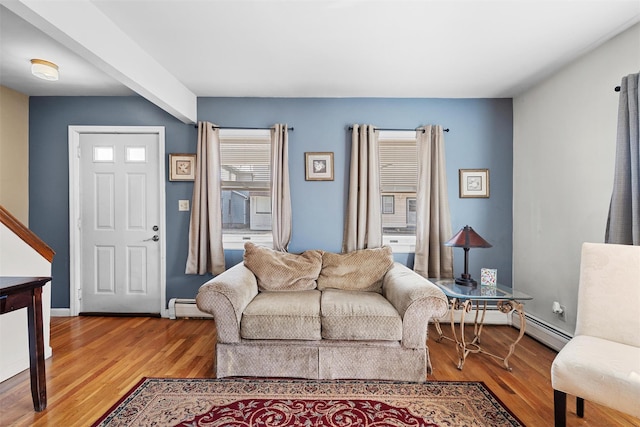 living area with a baseboard heating unit, light wood-style floors, and baseboards