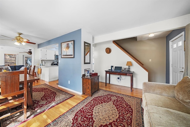 living room with a ceiling fan, light wood-type flooring, and baseboards