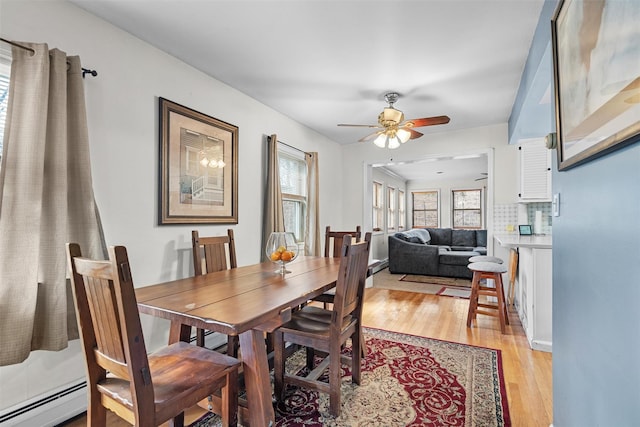 dining area featuring a baseboard heating unit, light wood-type flooring, and ceiling fan