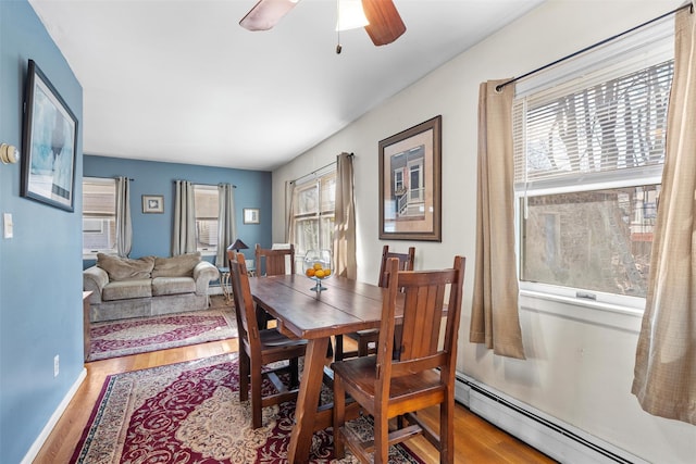 dining area with baseboard heating, wood finished floors, and a ceiling fan