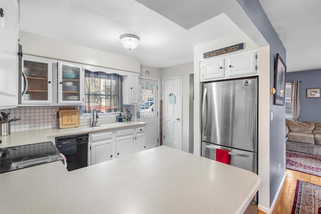 kitchen featuring light wood-style flooring, freestanding refrigerator, light countertops, dishwasher, and backsplash