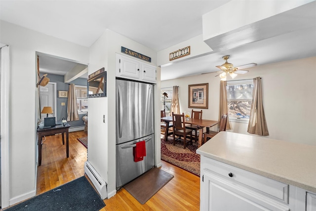 kitchen featuring white cabinetry, light wood finished floors, baseboard heating, and freestanding refrigerator