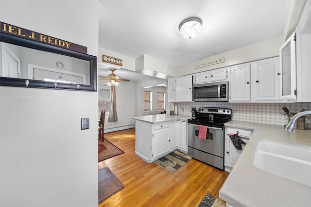 kitchen featuring a baseboard heating unit, a sink, white cabinetry, and stainless steel appliances