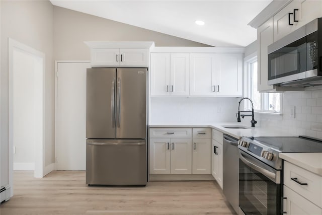 kitchen with light wood-style floors, vaulted ceiling, stainless steel appliances, and a sink