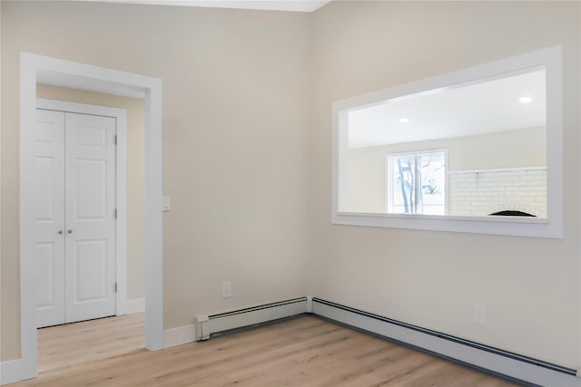 empty room with baseboard heating, recessed lighting, wood finished floors, and baseboards