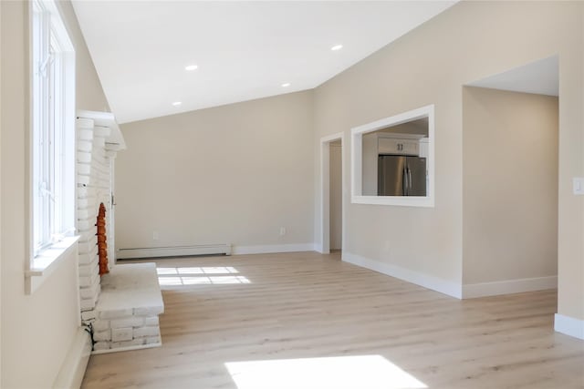 unfurnished living room featuring a baseboard heating unit, baseboards, and light wood-style floors