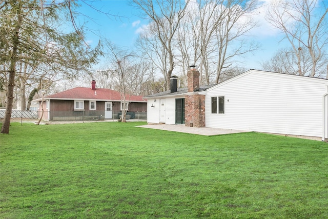 rear view of property featuring a patio area, a yard, a chimney, and fence