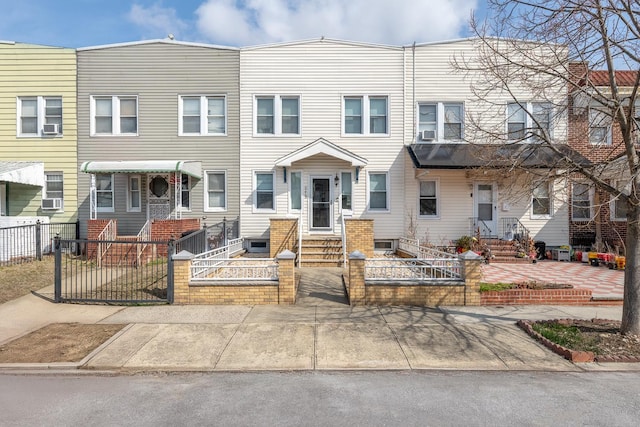 townhome / multi-family property featuring entry steps, a fenced front yard, and a gate