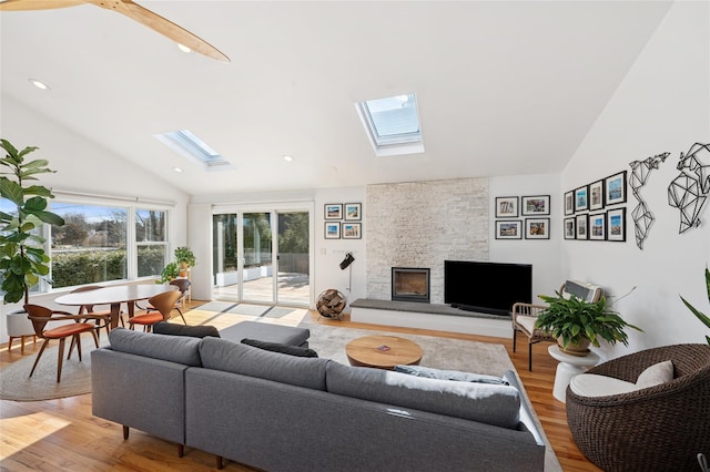 living area with recessed lighting, vaulted ceiling with skylight, a fireplace, and light wood-type flooring