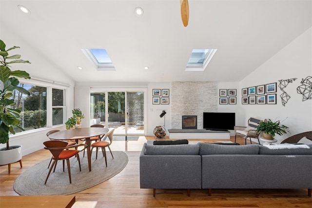 living room with lofted ceiling with skylight, recessed lighting, a fireplace, and light wood-type flooring