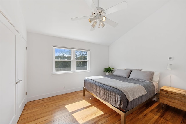 bedroom featuring baseboards, light wood-style flooring, a ceiling fan, and vaulted ceiling