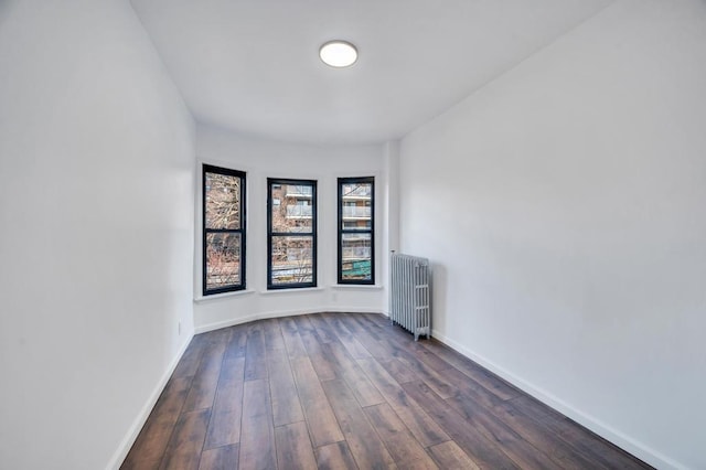 spare room with radiator, dark wood-style floors, and baseboards