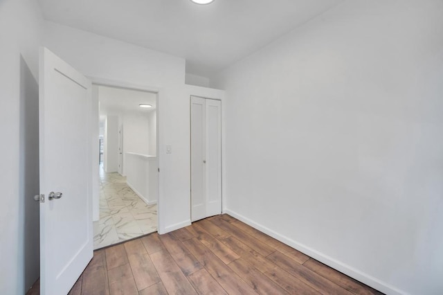 unfurnished bedroom with a closet, wood finished floors, and baseboards