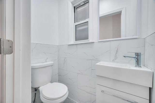 half bathroom with toilet, tile walls, and vanity