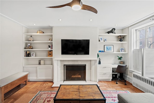 living area featuring built in features, recessed lighting, radiator, a high end fireplace, and ceiling fan