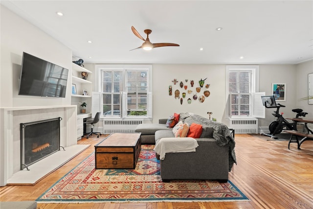 living room with a fireplace with raised hearth, radiator heating unit, and recessed lighting