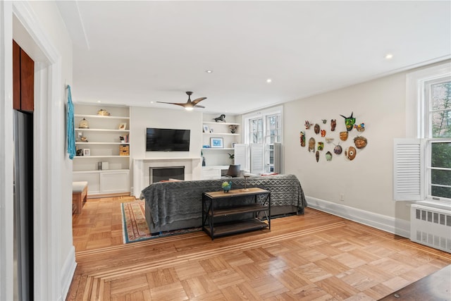 living area featuring radiator, plenty of natural light, baseboards, and built in features