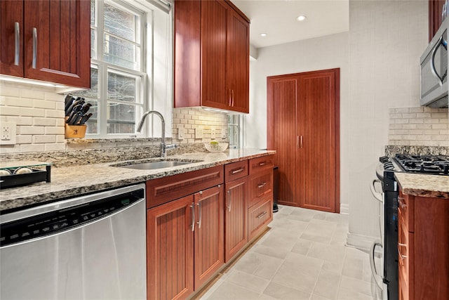 kitchen with light stone counters, recessed lighting, backsplash, appliances with stainless steel finishes, and a sink