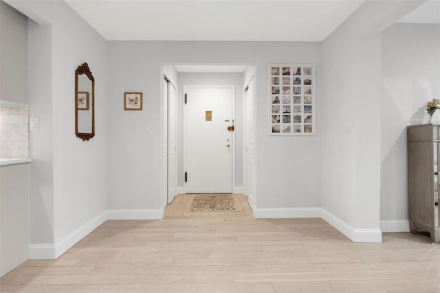 corridor featuring light wood-style flooring and baseboards