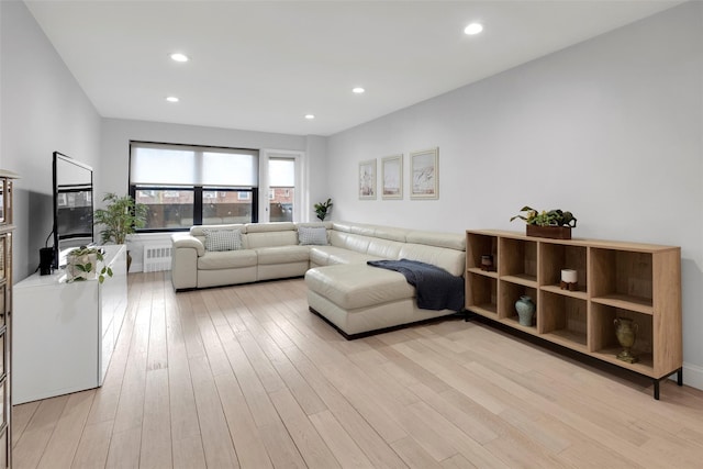 living room with light wood-style flooring, radiator heating unit, and recessed lighting