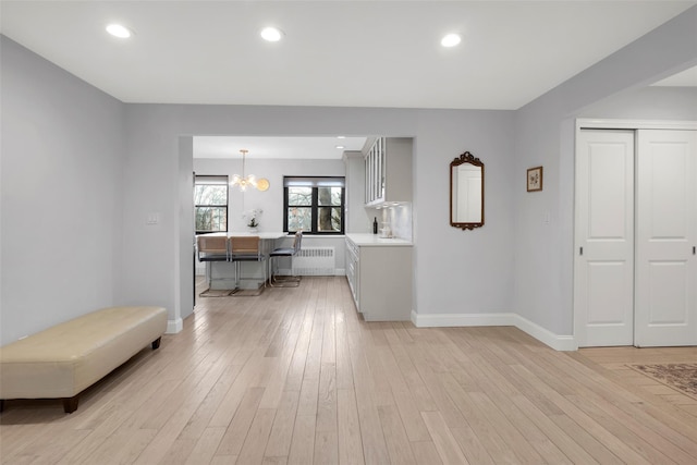 living room featuring recessed lighting, light wood-style flooring, radiator heating unit, an inviting chandelier, and baseboards