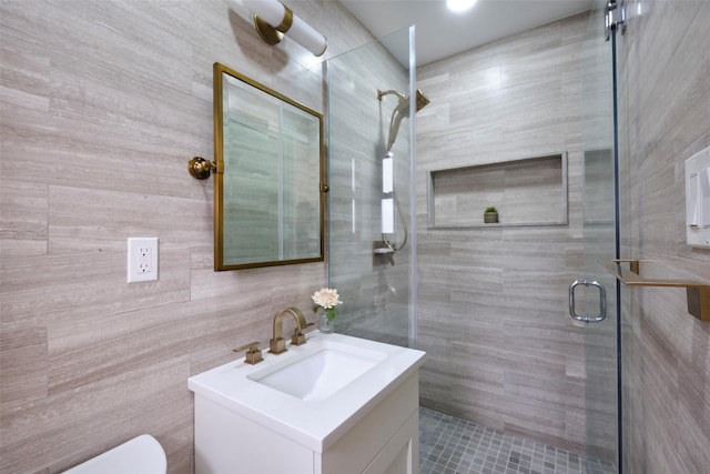 bathroom featuring tile walls, a shower stall, toilet, and vanity