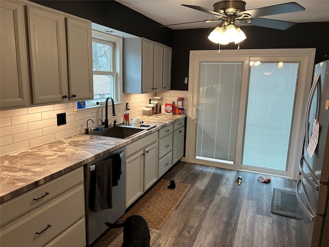 kitchen with dark wood finished floors, light countertops, decorative backsplash, stainless steel appliances, and a sink