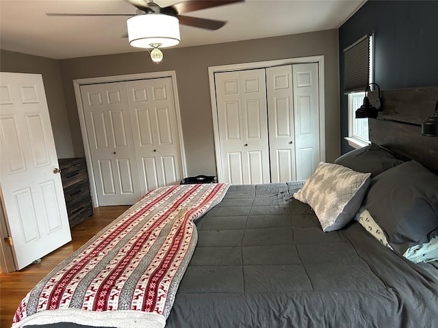 bedroom featuring a ceiling fan, dark wood finished floors, and two closets