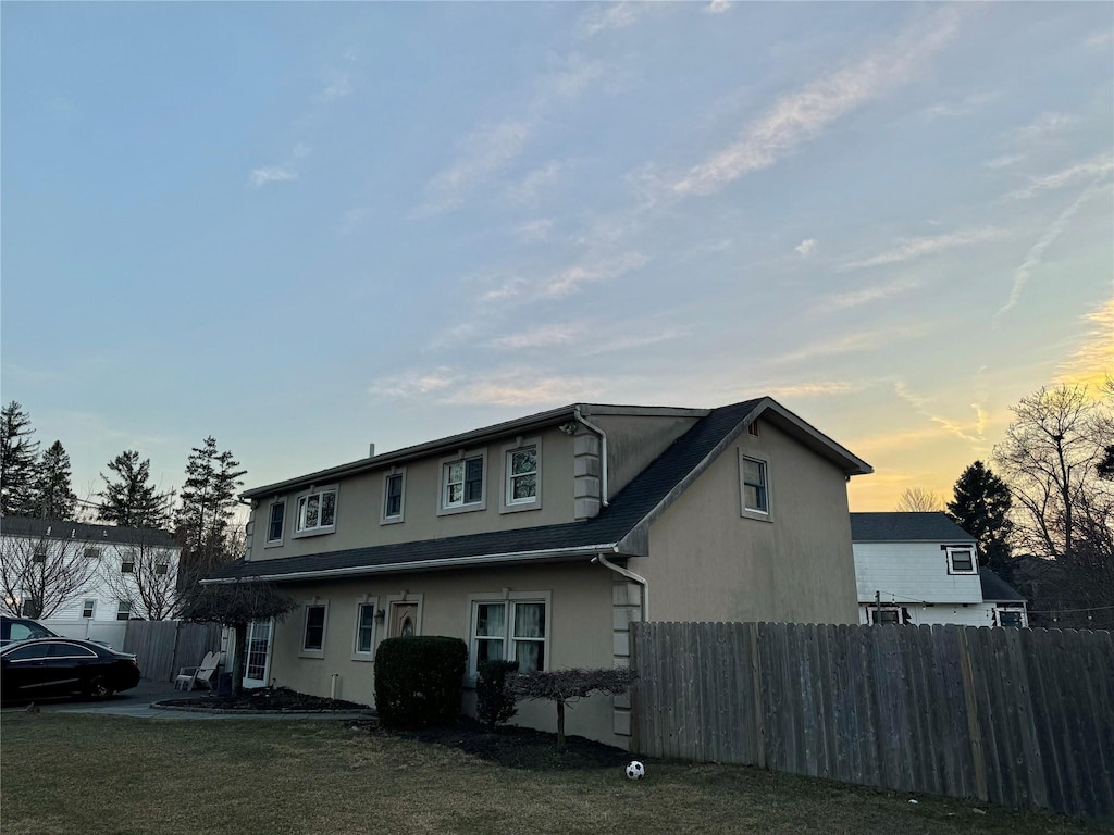 exterior space with a yard, fence, and stucco siding