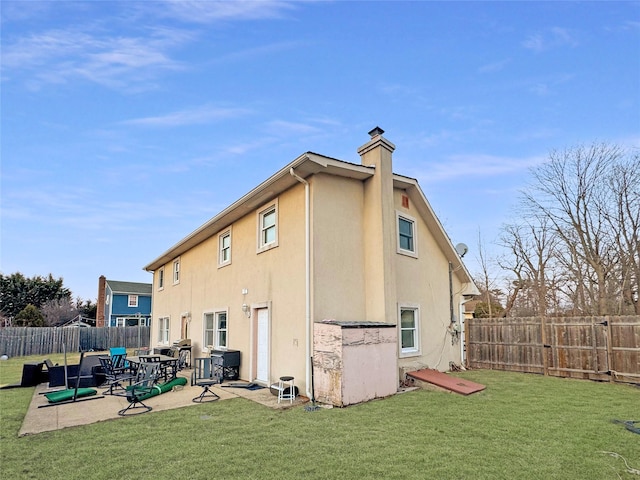 rear view of property featuring stucco siding, a yard, a fenced backyard, and a patio area