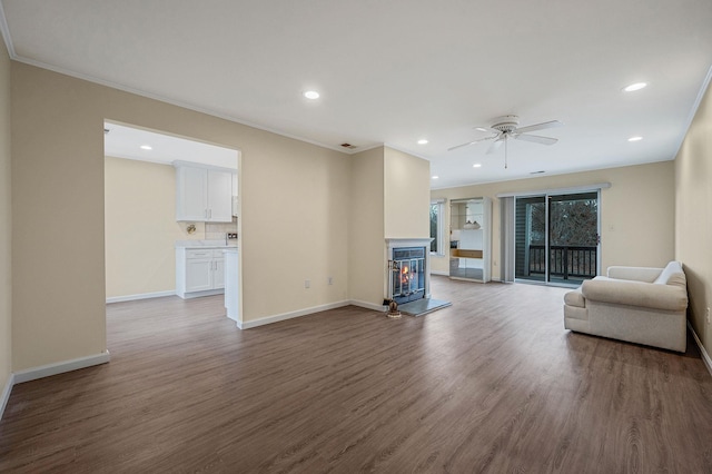 unfurnished living room featuring ornamental molding, baseboards, and wood finished floors