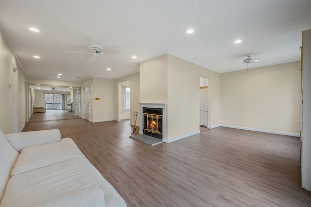 living area featuring recessed lighting, ornamental molding, a glass covered fireplace, ceiling fan, and wood finished floors